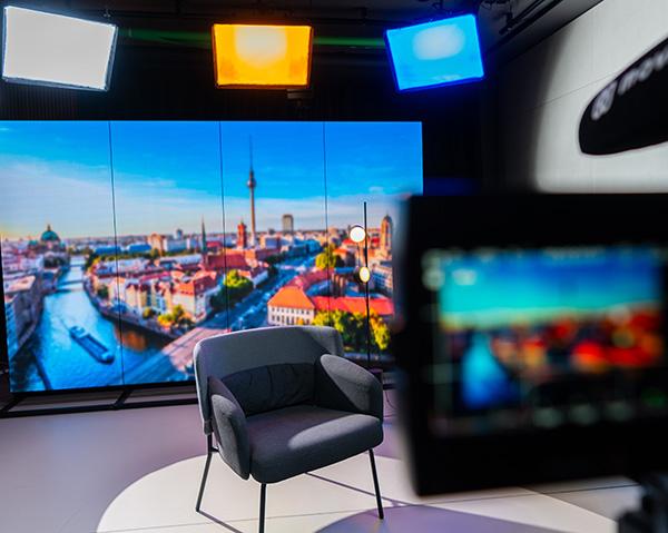 Movact.studio-Setup mit einem einzelnen Stuhl im Vordergrund und einem großen LED-Bildschirm, der eine Stadtlandschaft mit einem Fluss und einem Fernsehturm im Hintergrund zeigt.