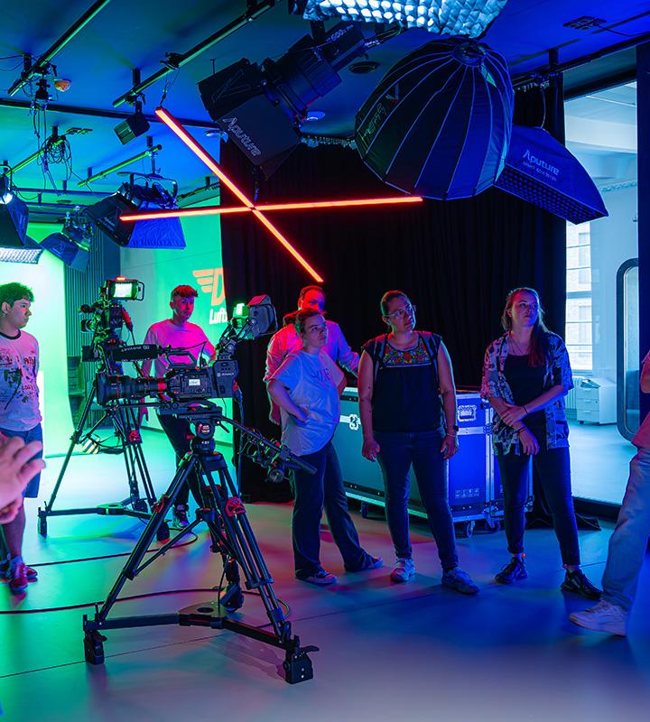 Group of people in a movact.studio with professional camera equipment and colorful lighting.